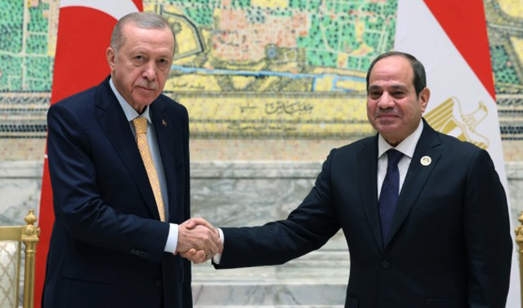 Cumhurbaşkanı Recep Tayyip Erdoğan ve Abdülfettah es-Sisi el sıkışırken görülüyor; arkada Türkiye ve Mısır bayrakları yer alıyor.