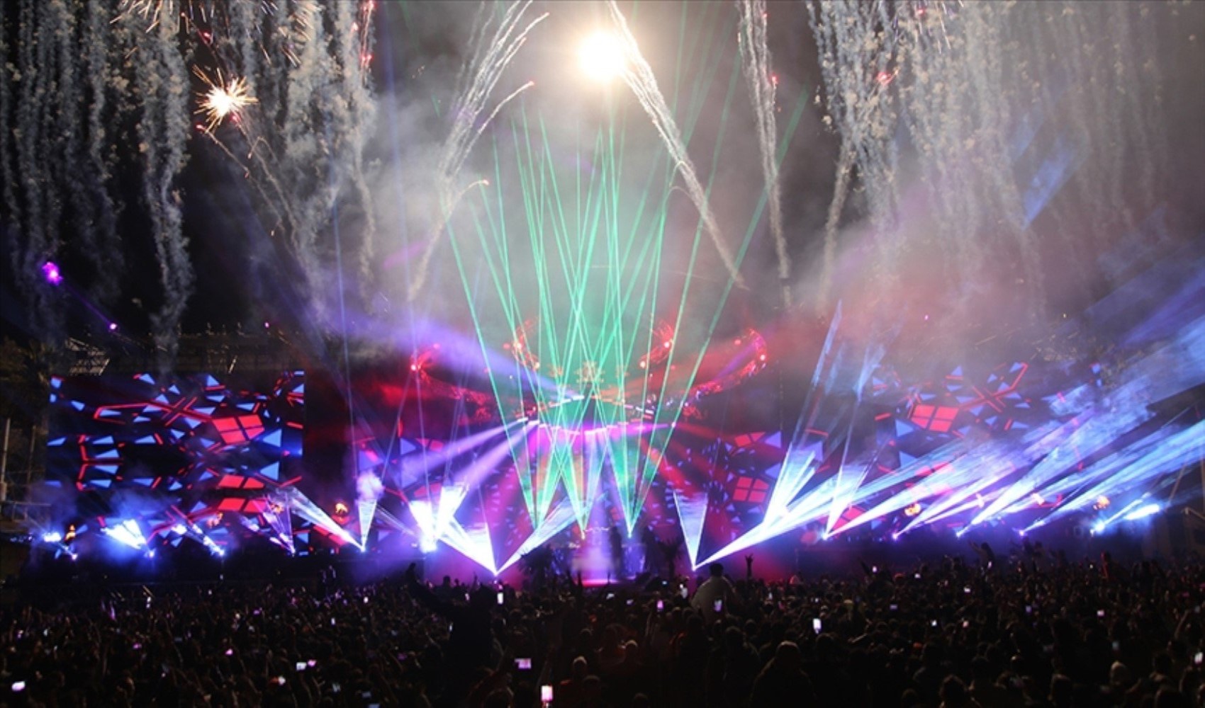 Kalabalık bir konser alanında ışık ve sahne gösterileri.