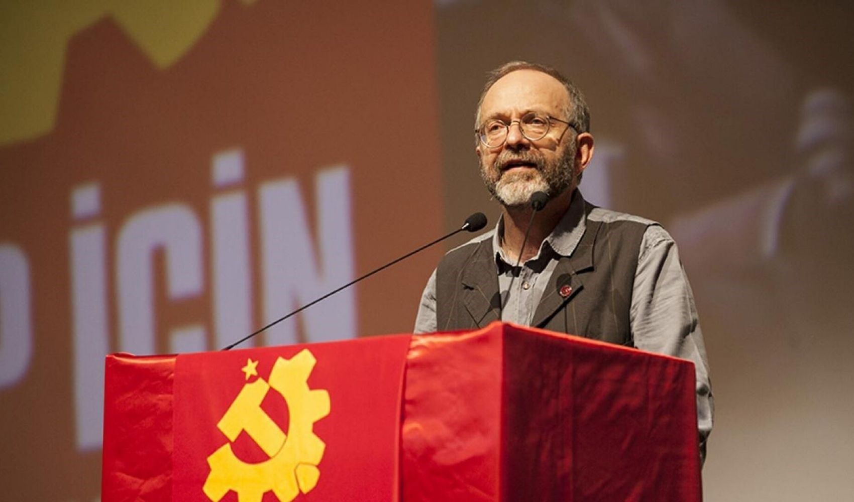 Kemal Okuyan’ın kürsüde konuşma yaptığı bir etkinlikten görüntü.