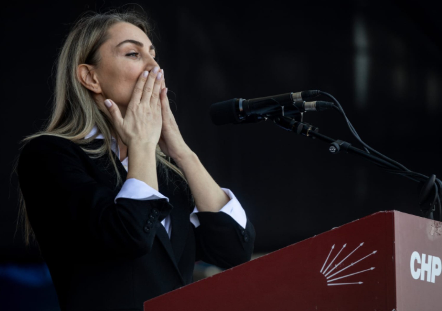 Dilek Kaya İmamoğlu’nun CHP logolu bir kürsü önünde mikrofonların yanında bulunduğu fotoğraf.