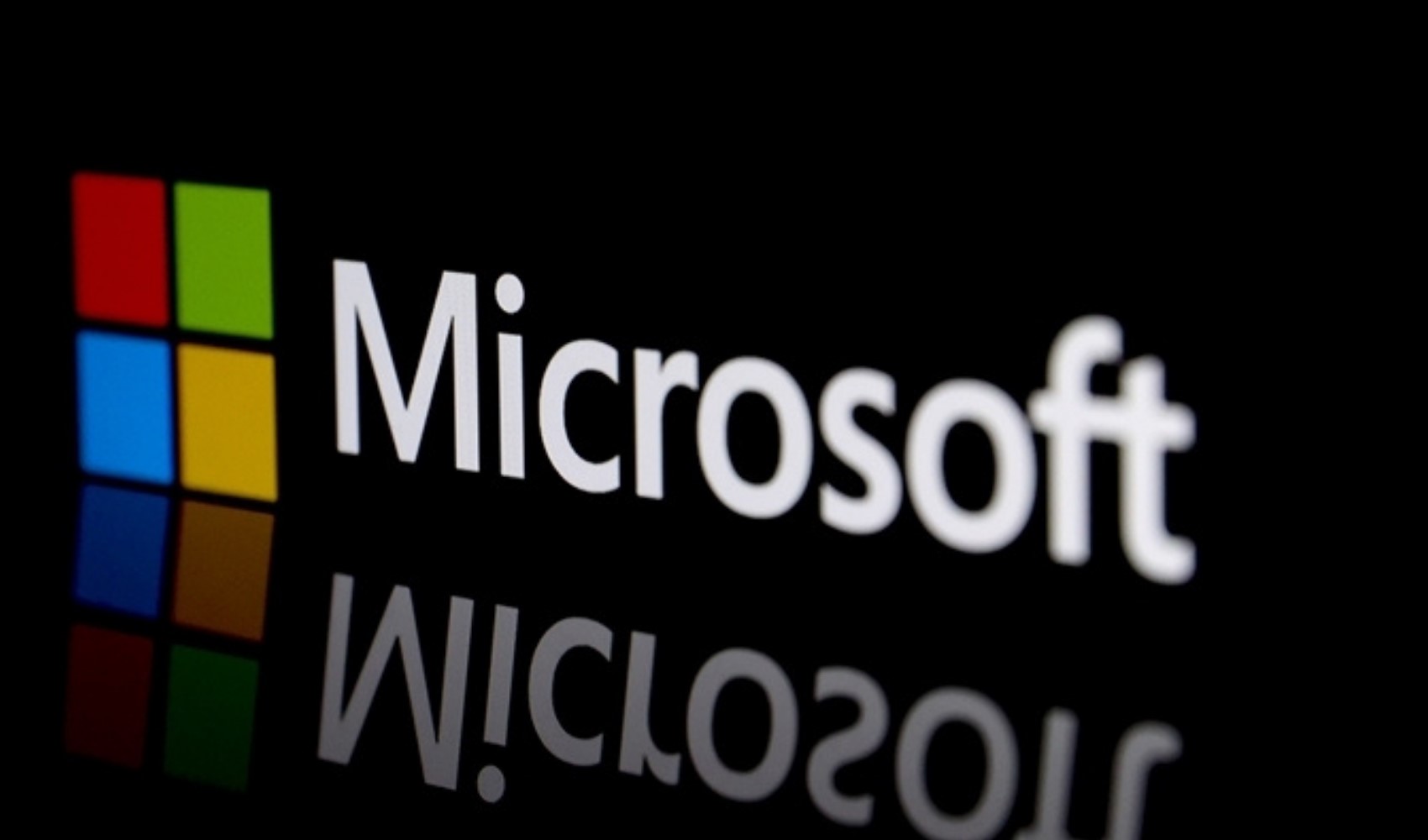 Microsoft logo and its reflection on a black background.