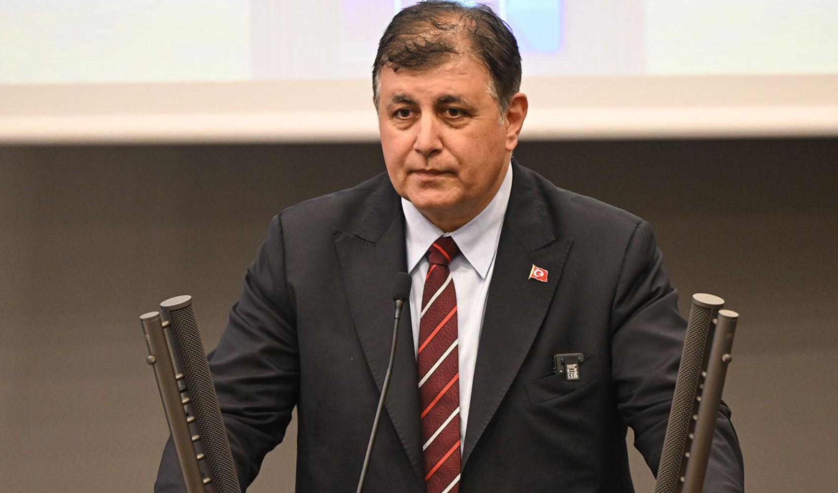 Cemil Tugay bir toplantıda mikrofonların önünde oturuyor.