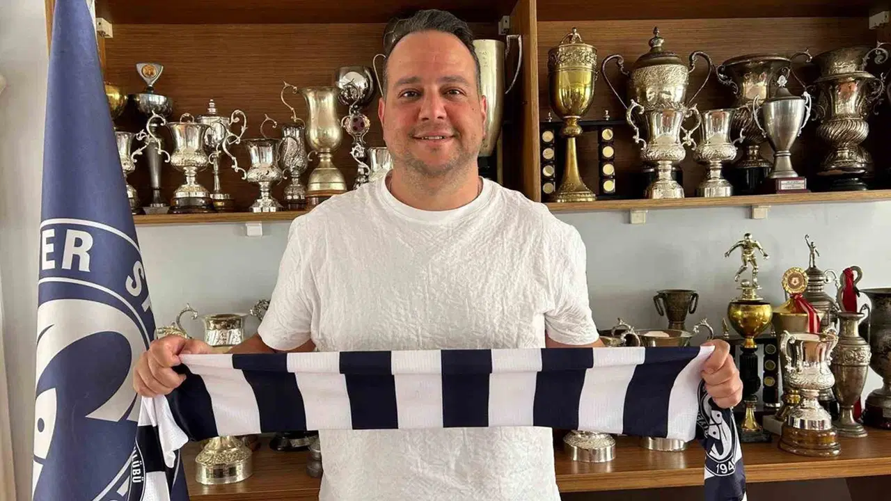 Sarıyer SK Başkanı Emre Yaldız, kupa dolabının önünde kulüp atkısıyla poz veriyor.