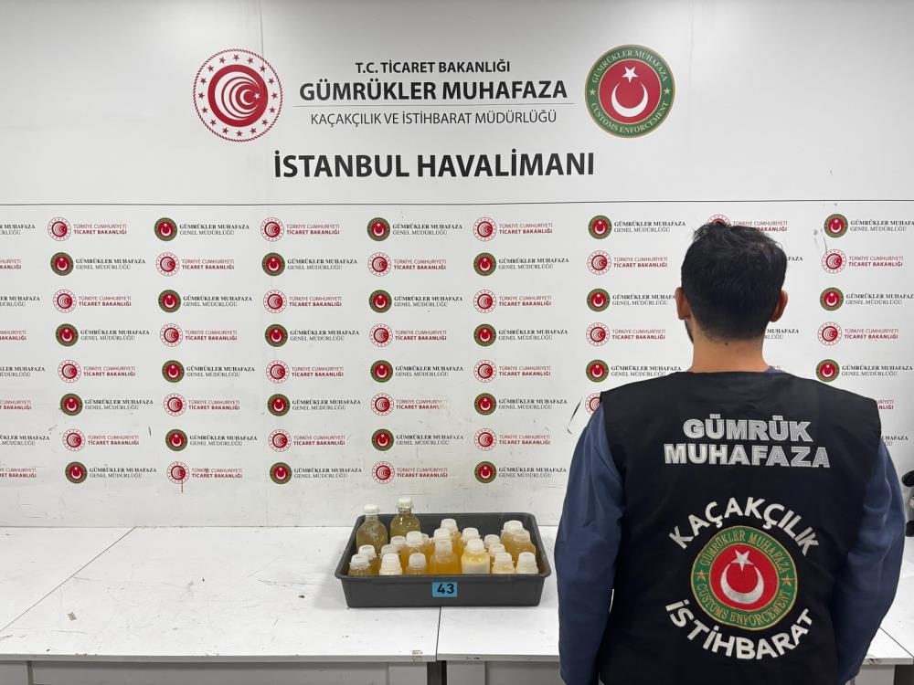 Ticaret Bakanlığı Gümrük Muhafaza birimi önünde ele geçirilen şişelerin ve bir görevlinin görüldüğü fotoğraf.