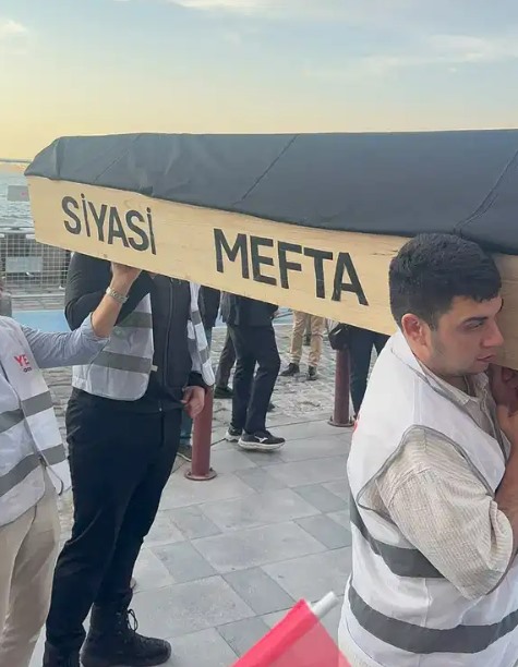 İzmir’deki protestoda üzerinde yazı bulunan tabut maketi taşıyan kişiler görülüyor.