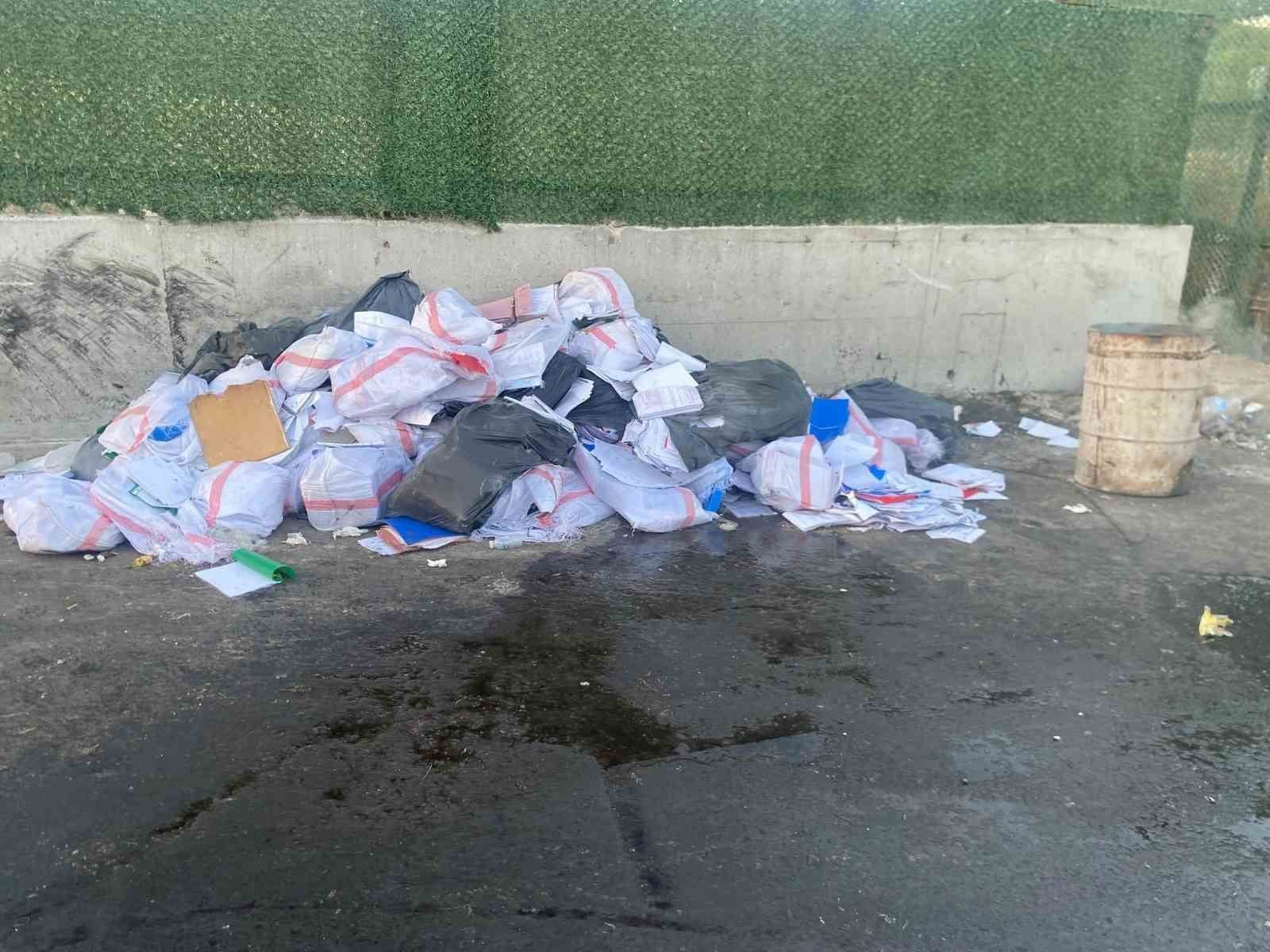 A large number of documents and piles of paper are seen in bags next to trash.