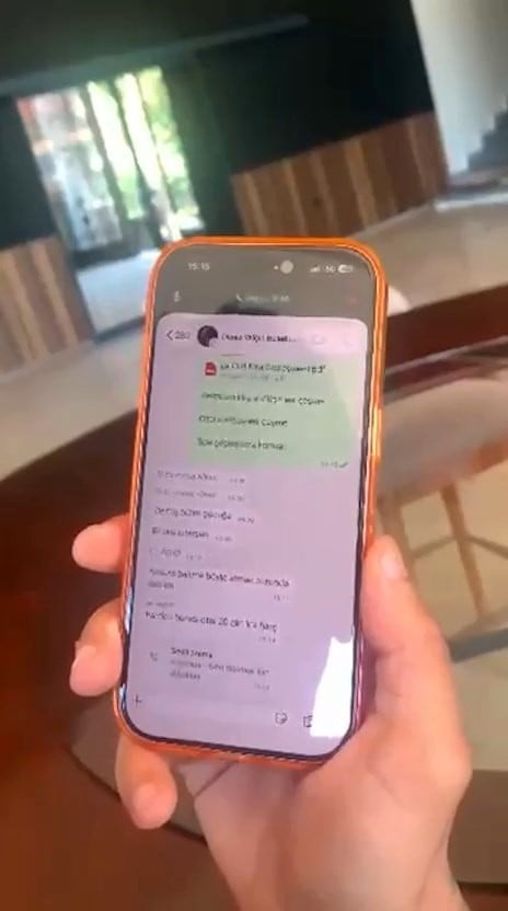 WhatsApp correspondence is seen on a phone held in a person's hand.