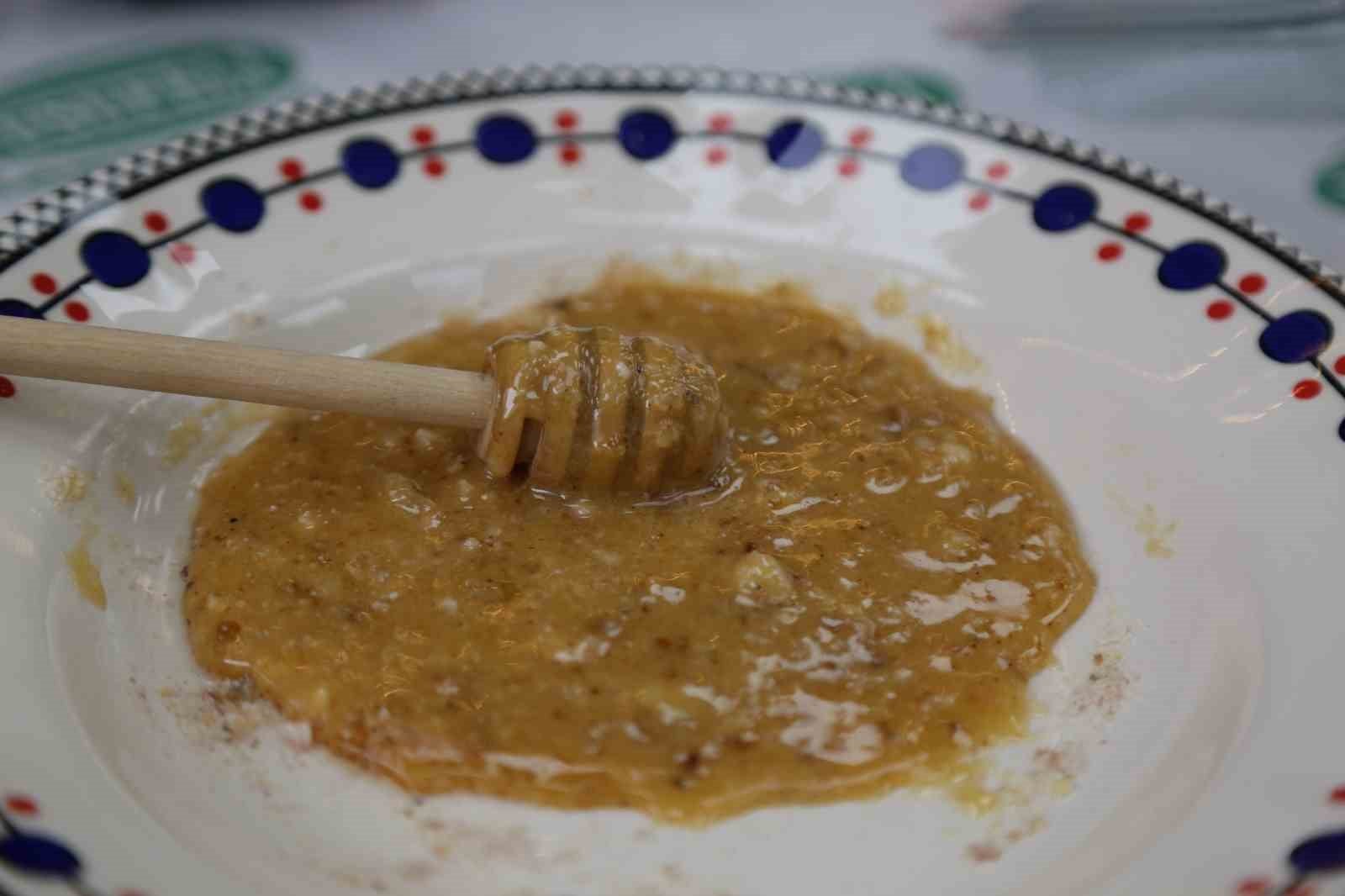 Desenli bir tabakta bal ile karıştırılmış çam sakızı ve tahta karıştırıcı.
