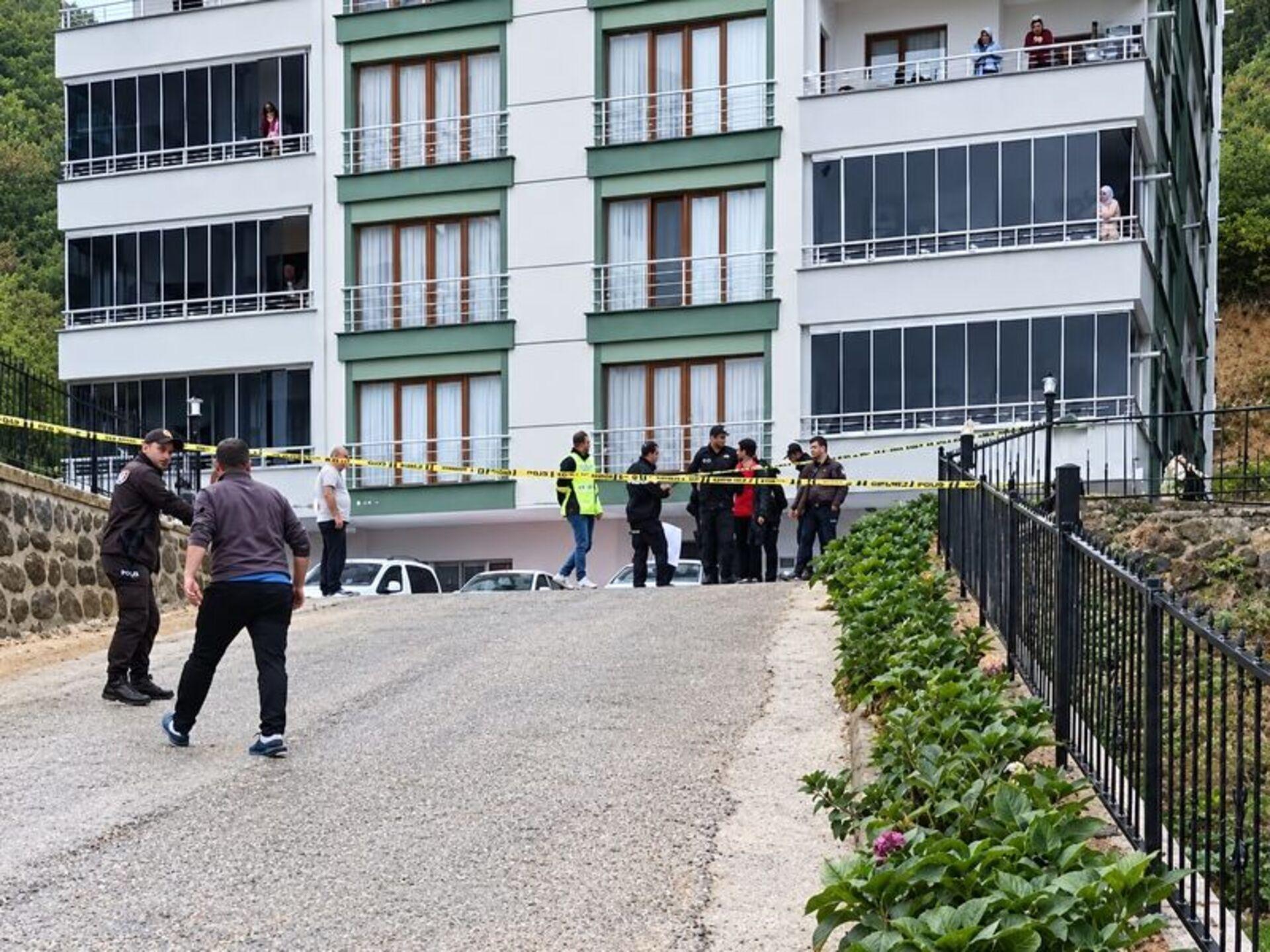 Police teams and a security cordon are seen in front of an apartment building.
