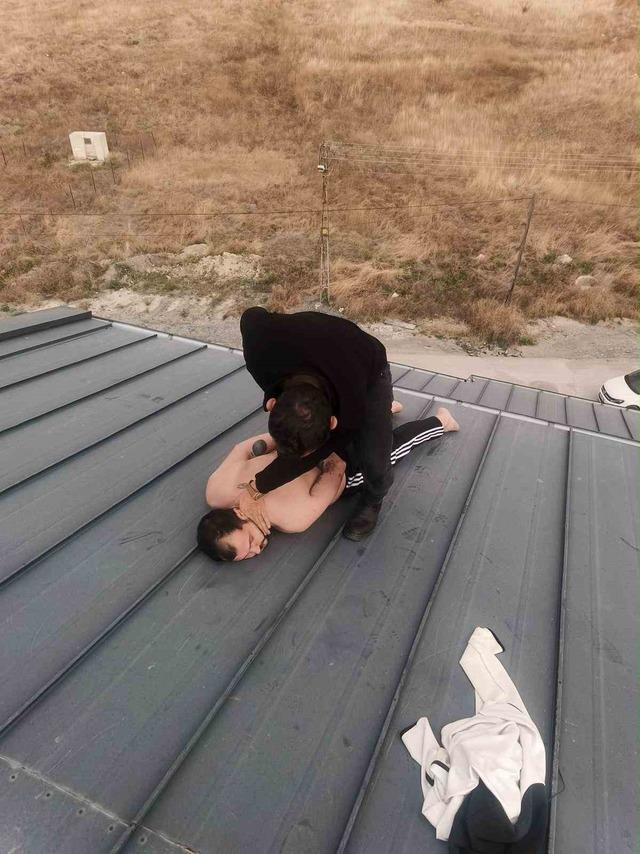 A person is seen being neutralized by police on a roof.