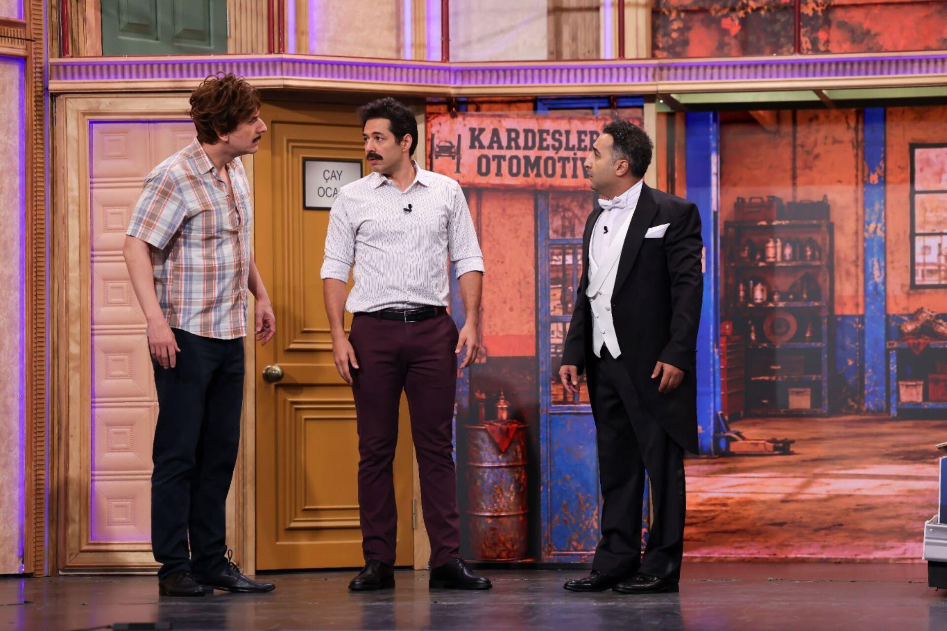Güldür Güldür Show sahnesinde üç oyuncunun dekor önünde yer aldığı skeç görüntüsü.