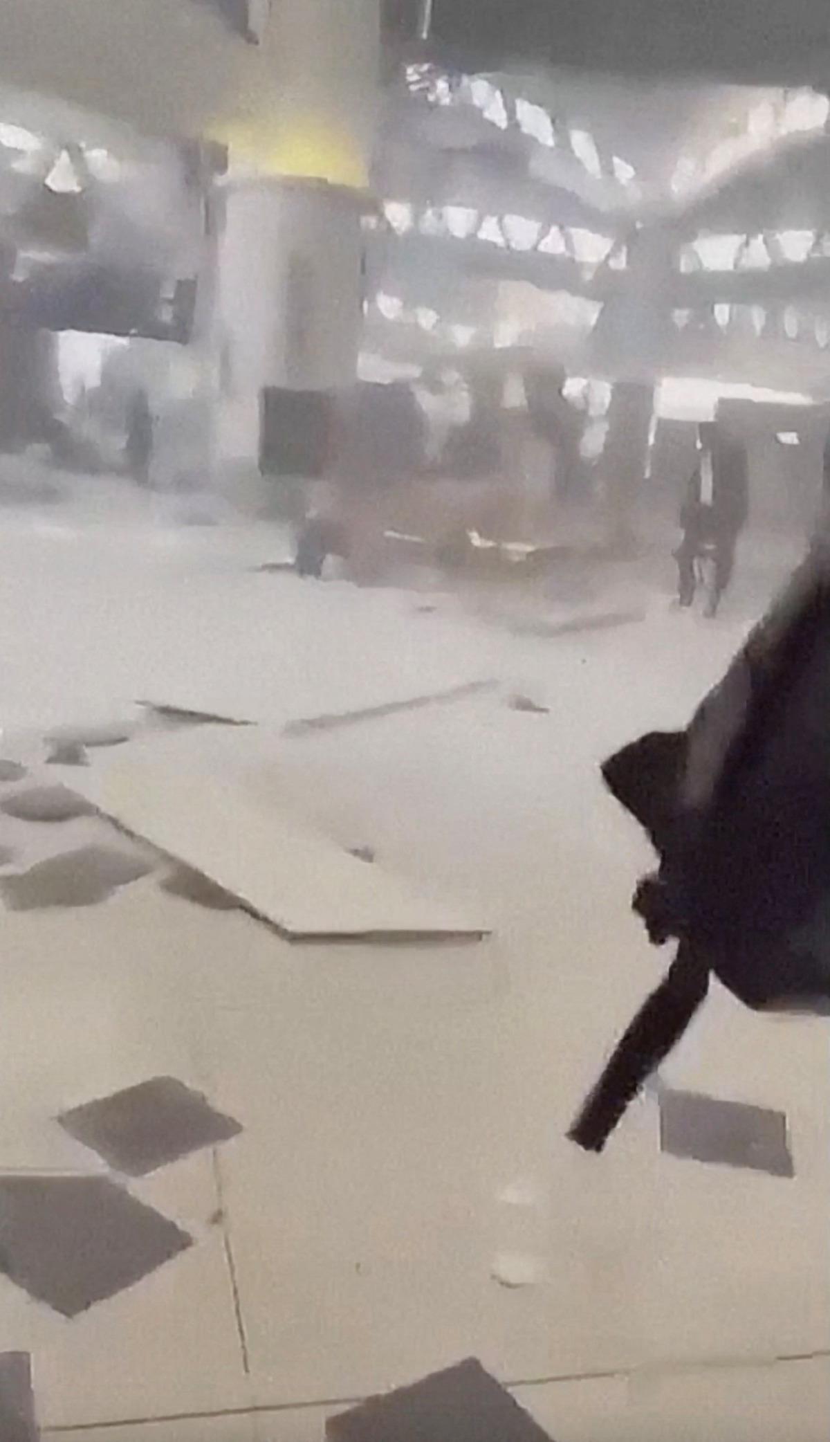 Havalimanı terminalinde duman, döküntüler ve içeride hareket eden kişilerin görüldüğü bulanık görüntü.