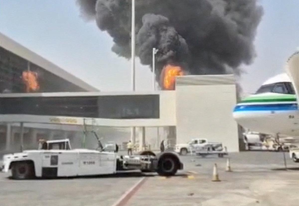 Kral Halid Havalimanı terminal binası yakınında alevler ve yoğun siyah duman, apronda uçak ve yer hizmetleri aracı.