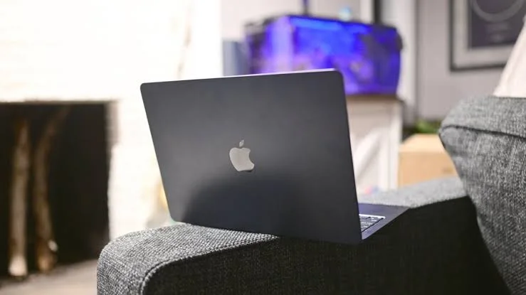 Un portatile Apple di colore nero appoggiato su una poltrona.
