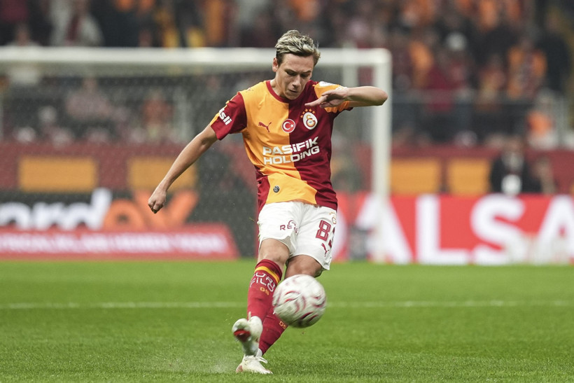 Galatasaray forması giyen futbolcu maç sırasında topa müdahale ediyor.