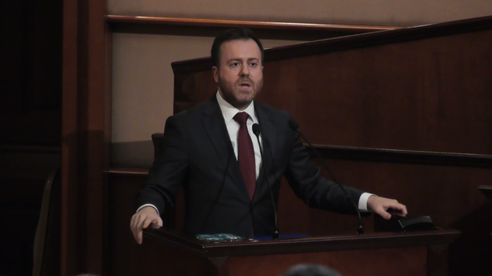 Ali Şar mentre parla al microfono dal podio dell'Assemblea dell'IMM.