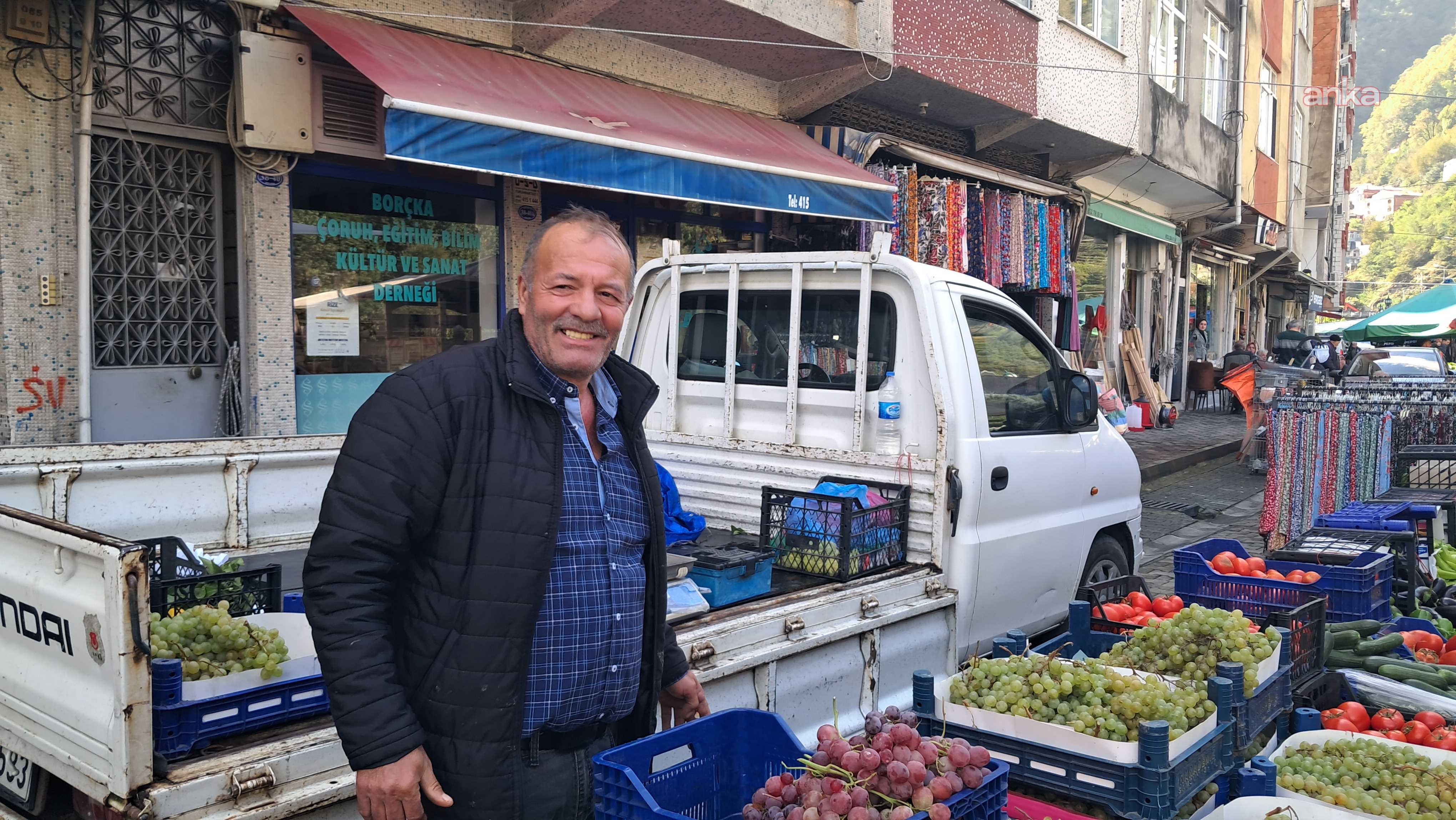 Un banco del mercato con cassette di frutta e verdura e un cittadino a Borçka.