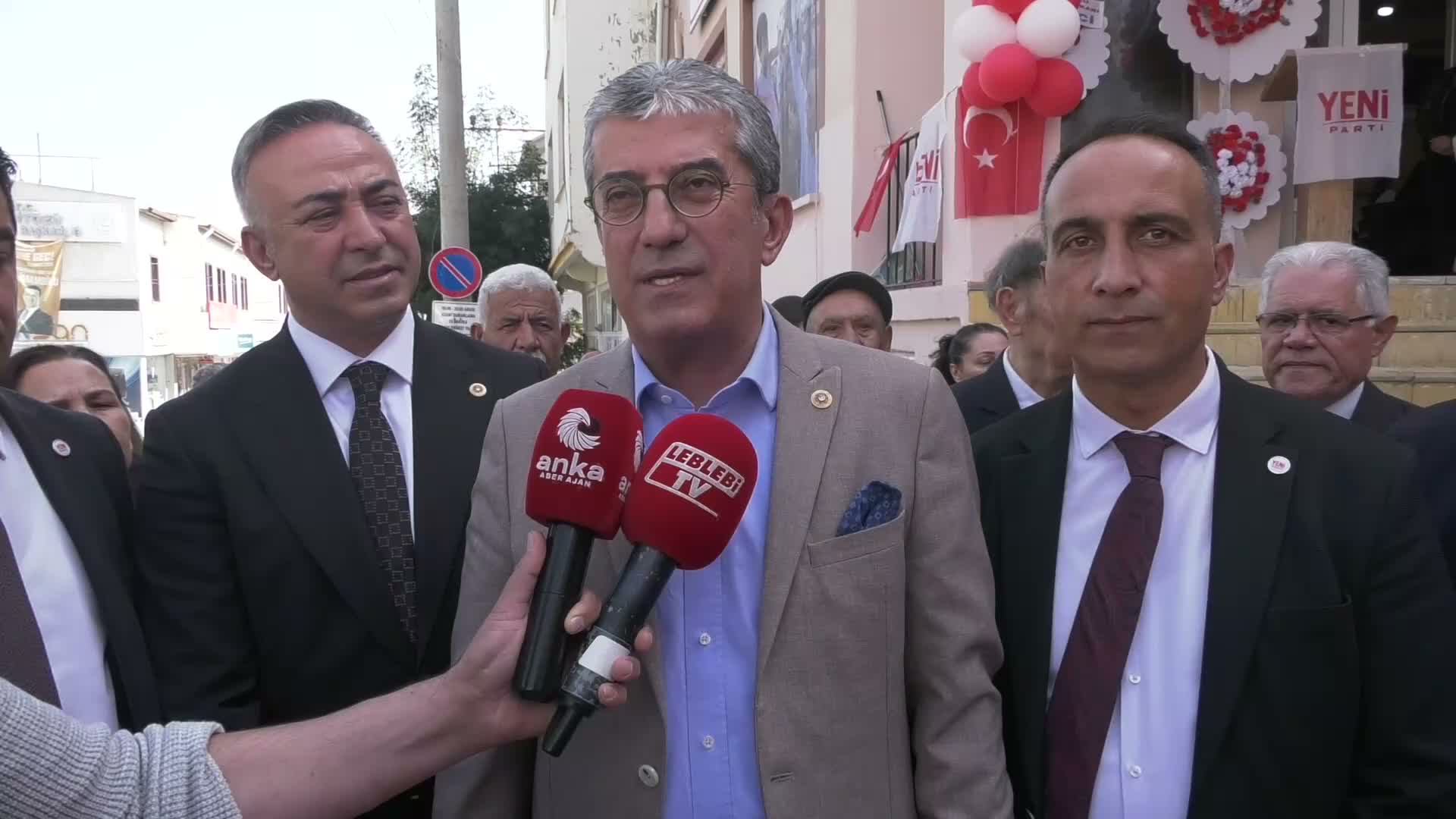 Gökhan Günaydın parla ai microfoni davanti alla sede distrettuale di YENİ Parti a Mecitözü.