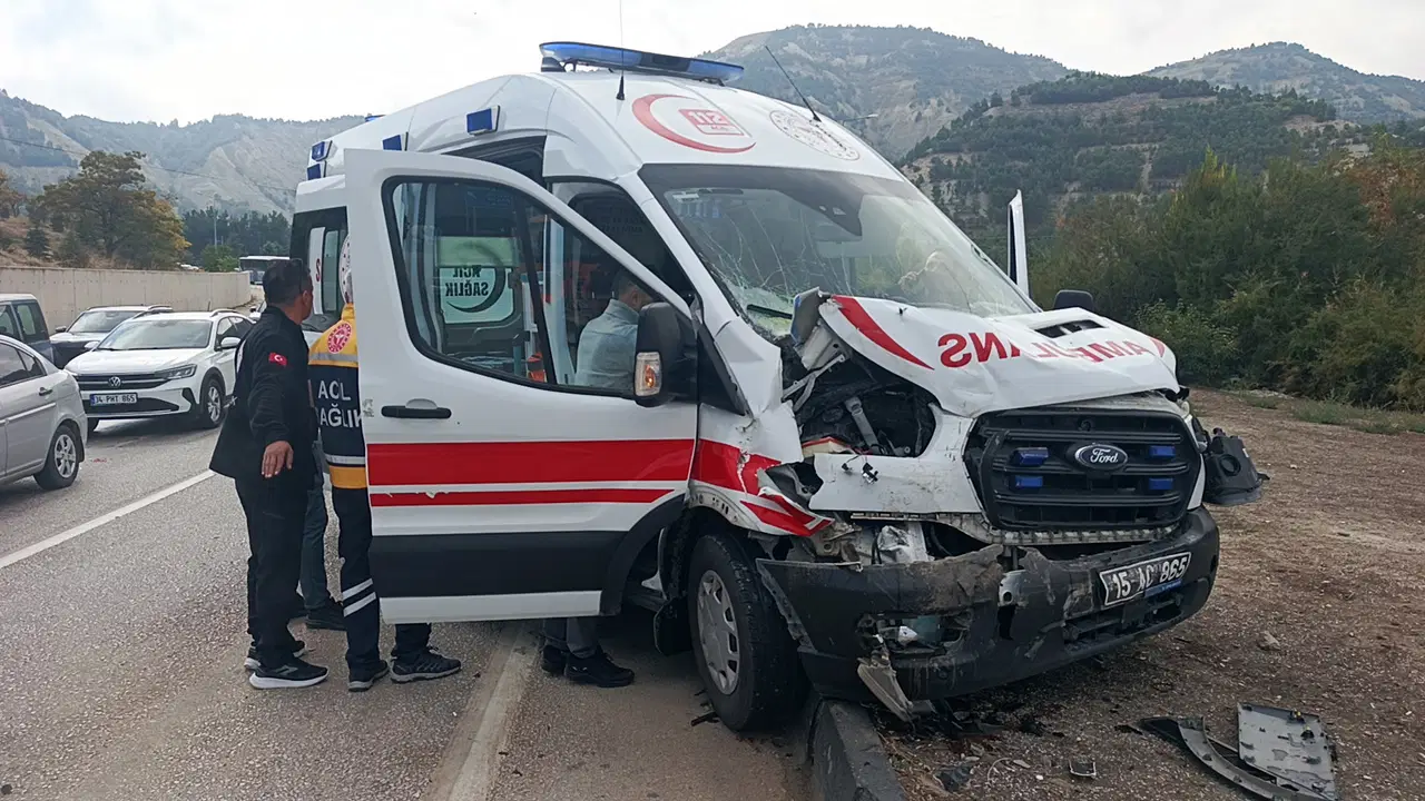 Ön kısmı hasar gören ambulansın yol kenarında durduğu ve görevlilerin araç çevresinde bulunduğu görüntü.