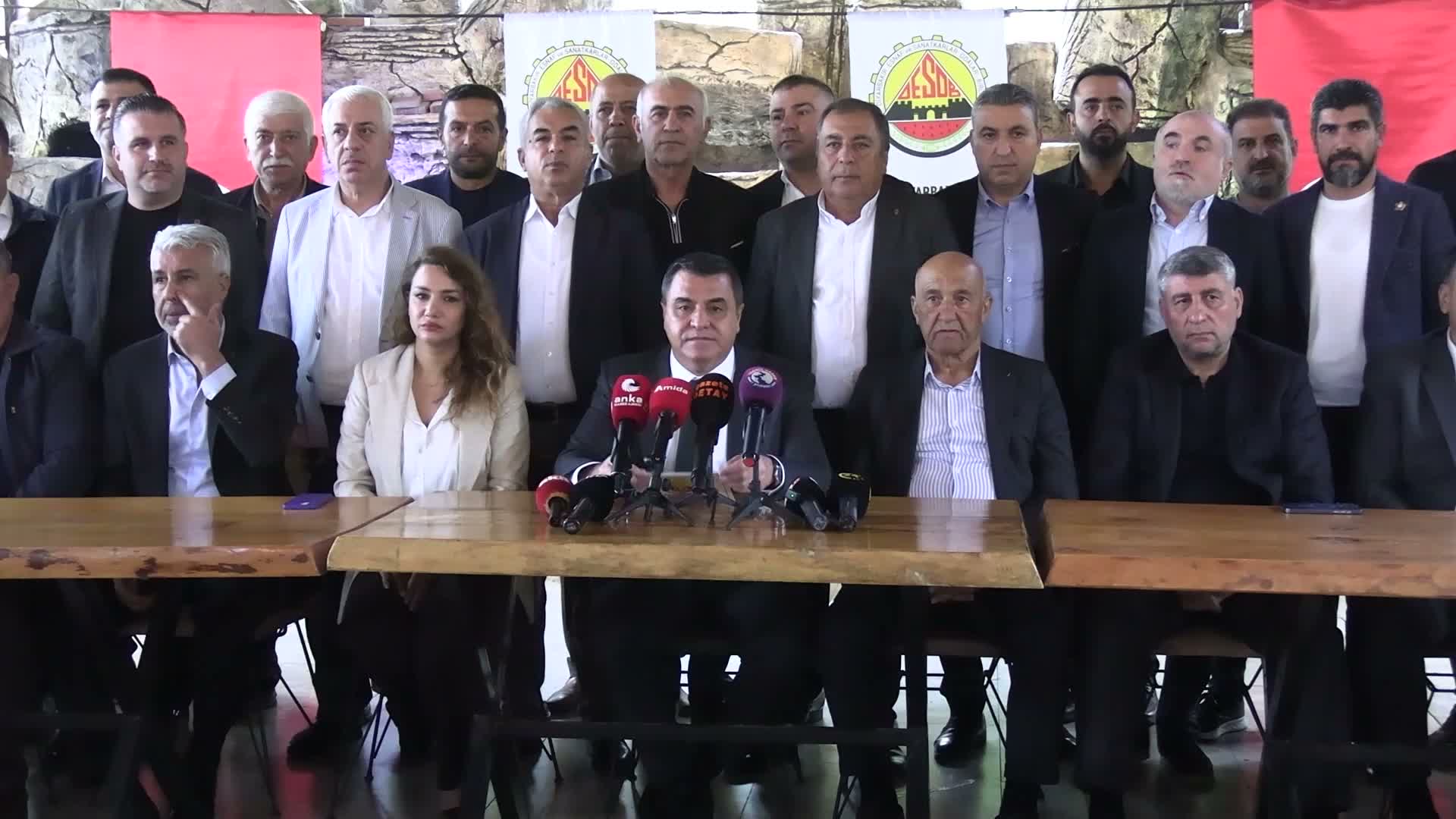 DESOB temsilcileri ve esnaf odası yöneticileri basın toplantısında mikrofonların bulunduğu masanın çevresinde yer alıyor.