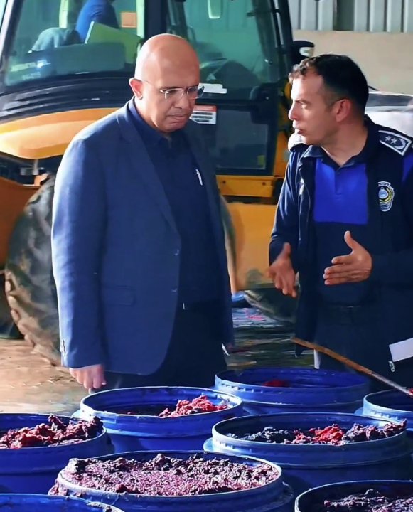 Officials examining food products kept in blue containers inside the warehouse.