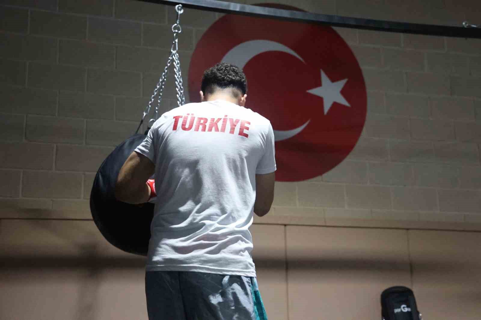 Mert Can Akarsu, Türk bayrağının bulunduğu duvar önünde kum torbasıyla çalışıyor.