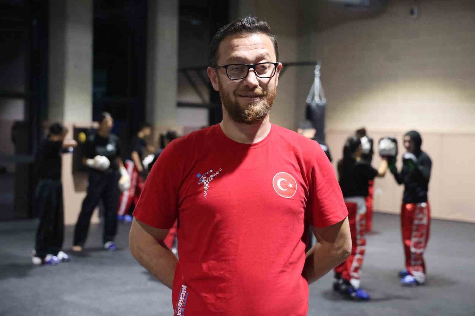 Kick boks antrenörü Mevlüt Aker, salonda sporcuların önünde açıklama yaparken görülüyor.