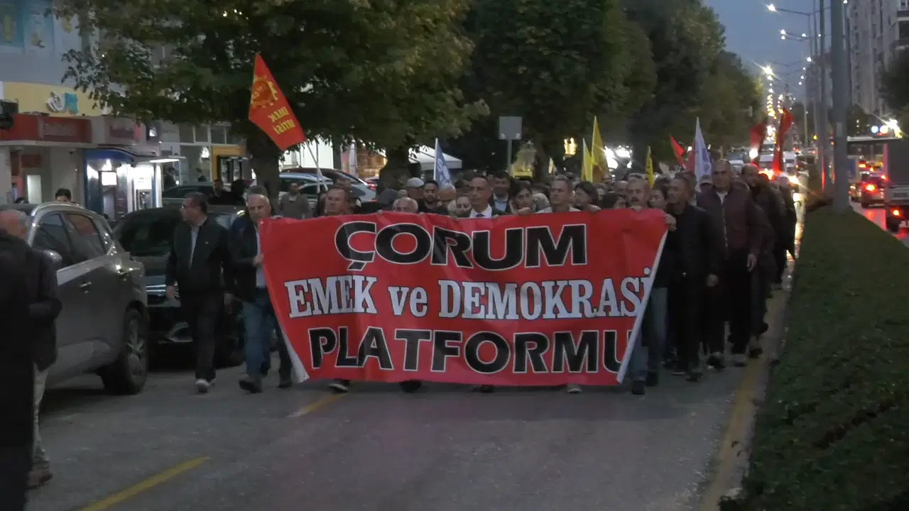 Çorum’da akşam saatlerinde yürüyen kalabalık, kırmızı pankart taşıyor.