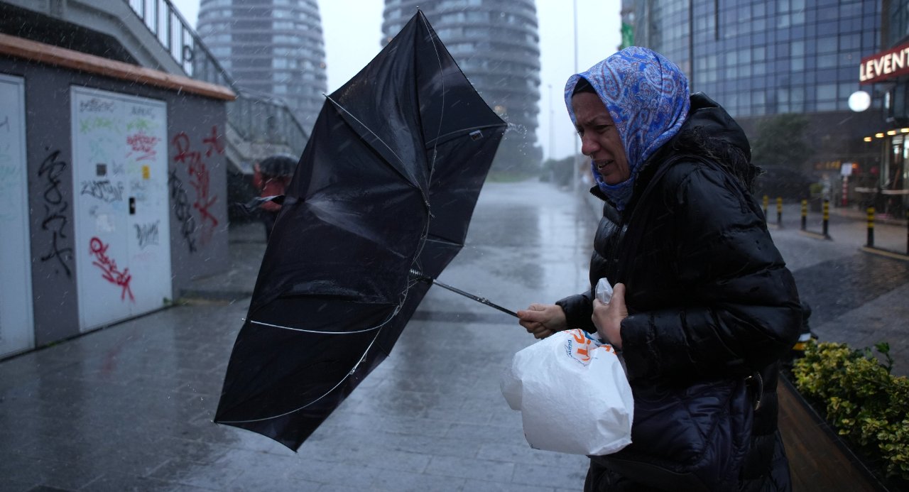 Şiddetli yağmur altında şemsiye ile yürüyen bir kişi.
