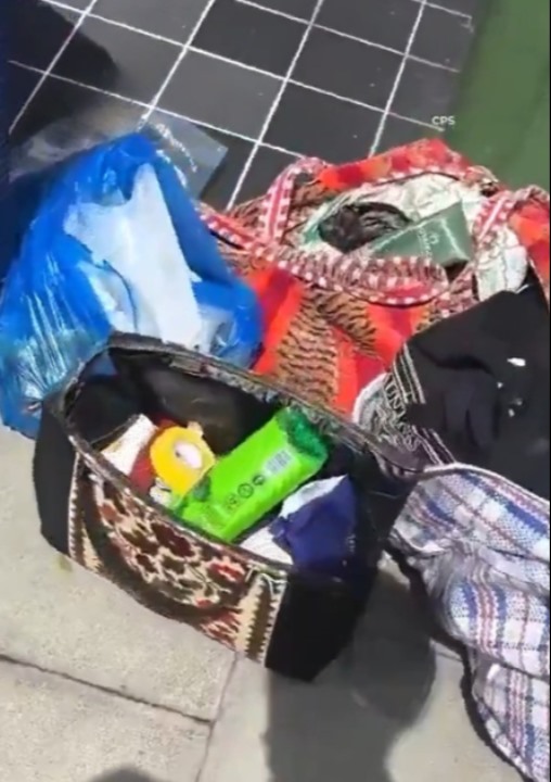 Kaldırımda bulunan çanta ve kişisel eşyaları gösteren görüntü.