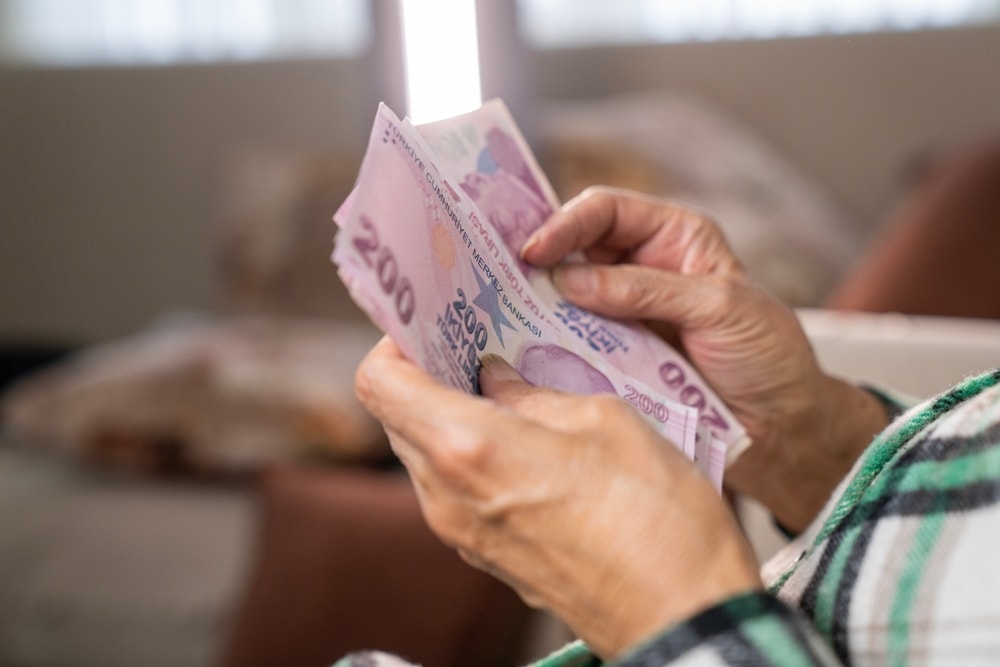A retired person holding Turkish lira banknotes.