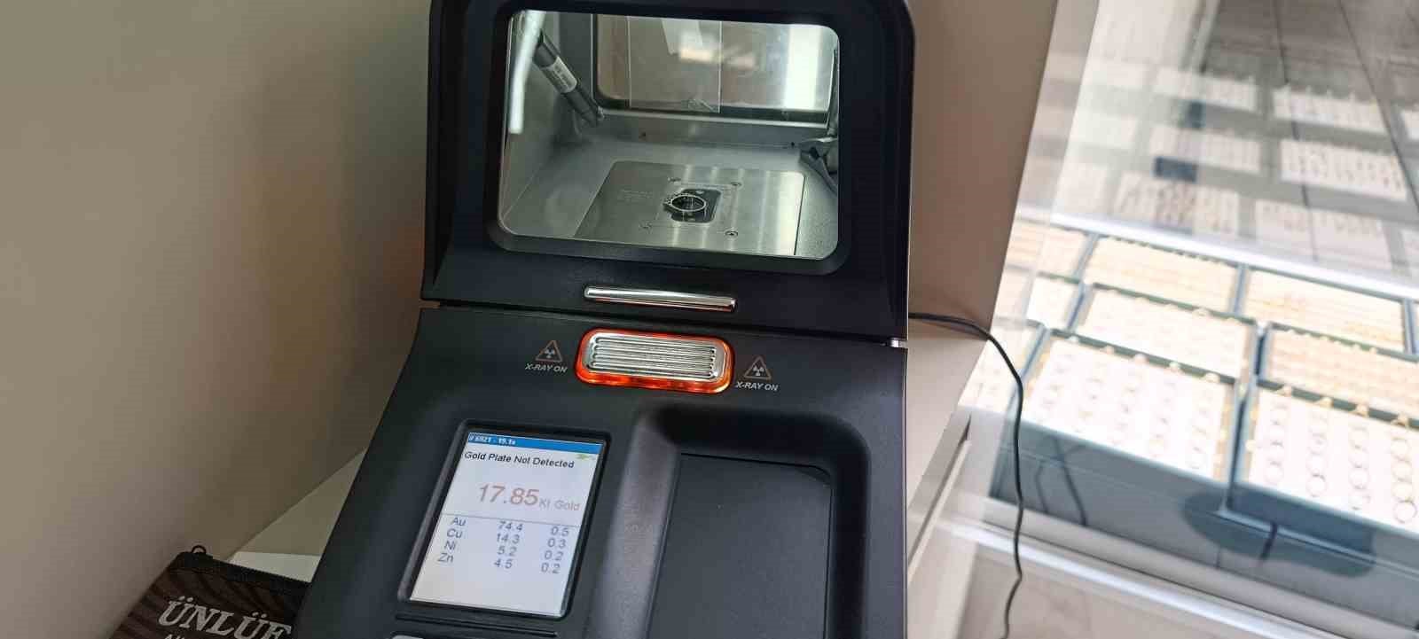 The screen of a gold karat measurement device and the control area next to a jeweler's counter are seen.