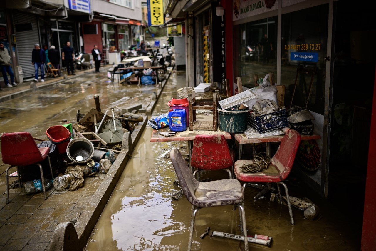 Una strada in cui si vedono acqua fangosa e oggetti dopo un nubifragio.