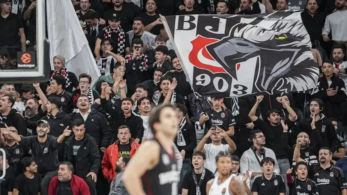 Beşiktaş basketball fans supporting their team with flags in the stands.