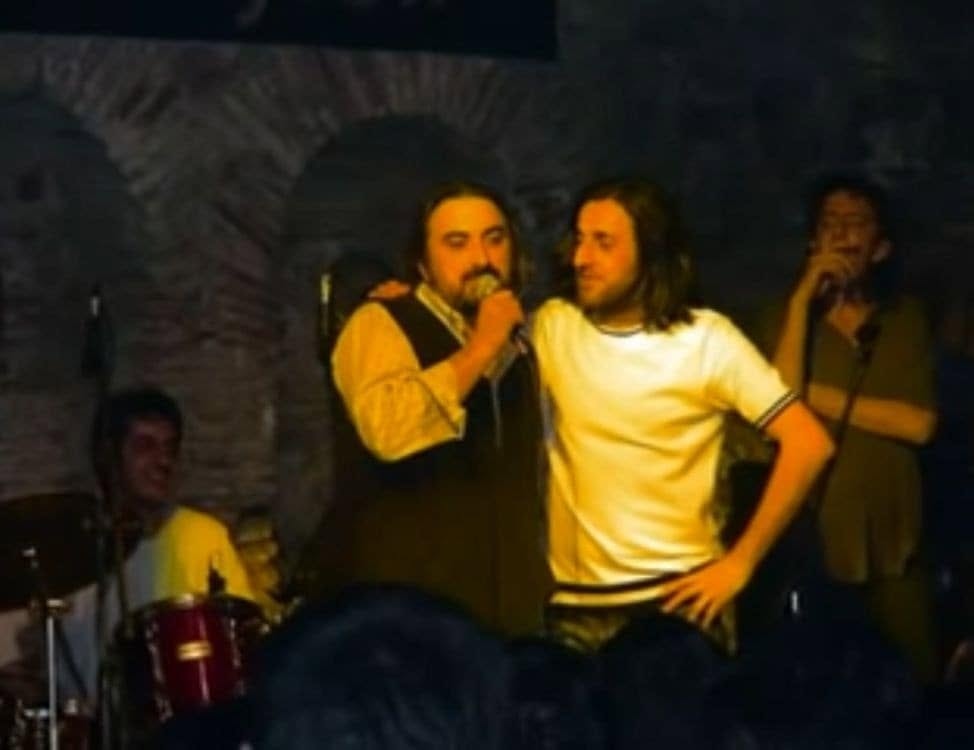 Kazım Koyuncu ve Volkan Konak'ın sahnede mikrofonlarla görüldüğü eski konser fotoğrafı.