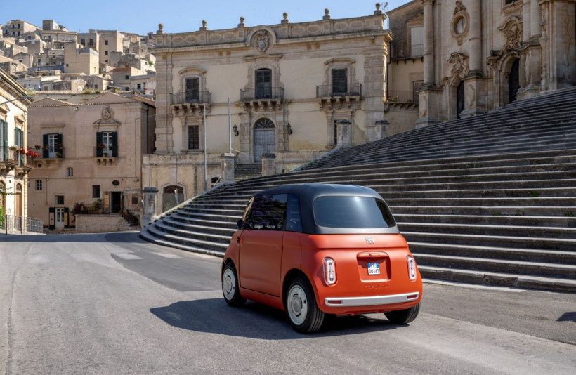 Tarihi bir meydanda görülen turuncu Fiat Topolino.
