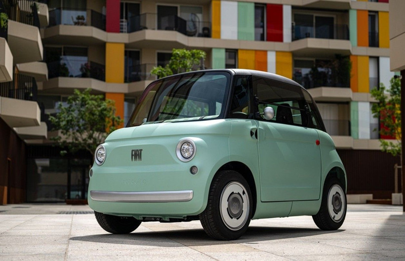 Modern bir bina önünde park halinde açık yeşil Fiat Topolino.