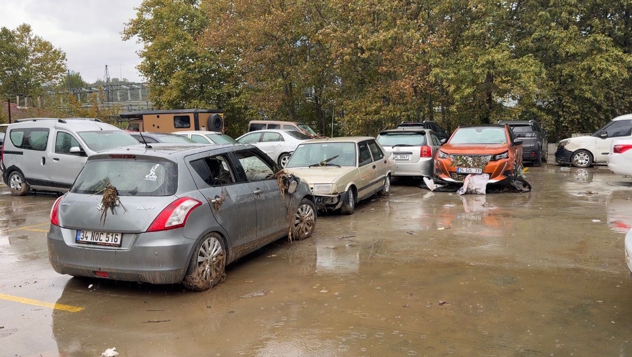 The parking area containing vehicles damaged and covered in mud after the flood.