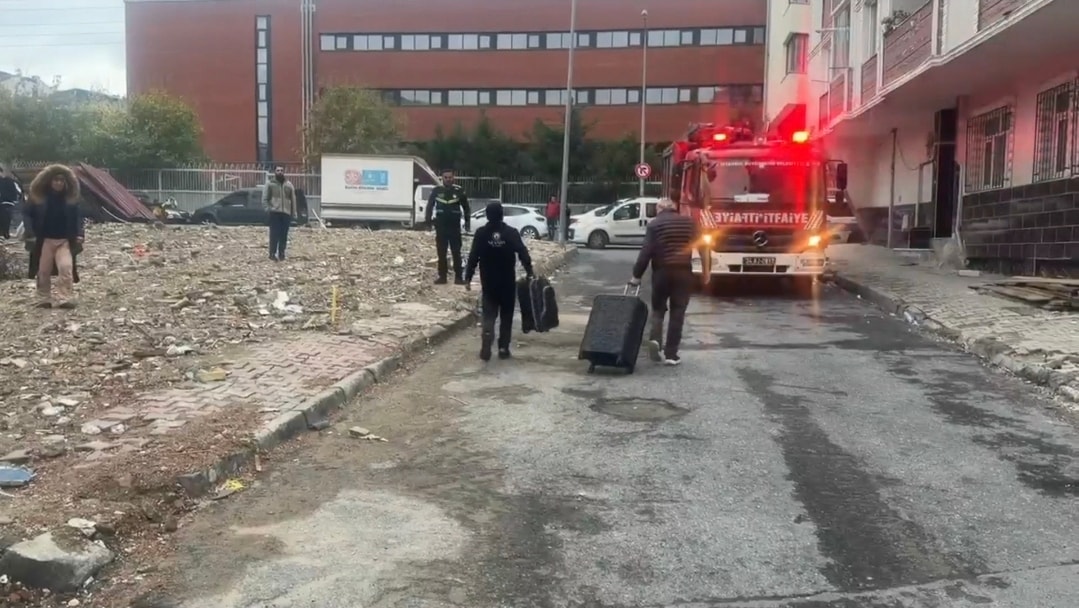 İtfaiye aracının bulunduğu sokakta eşyalarıyla ilerleyen bina sakinleri.