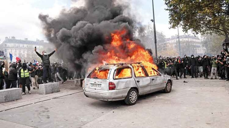 A burning vehicle and protesters gathered around it during the protests in France.