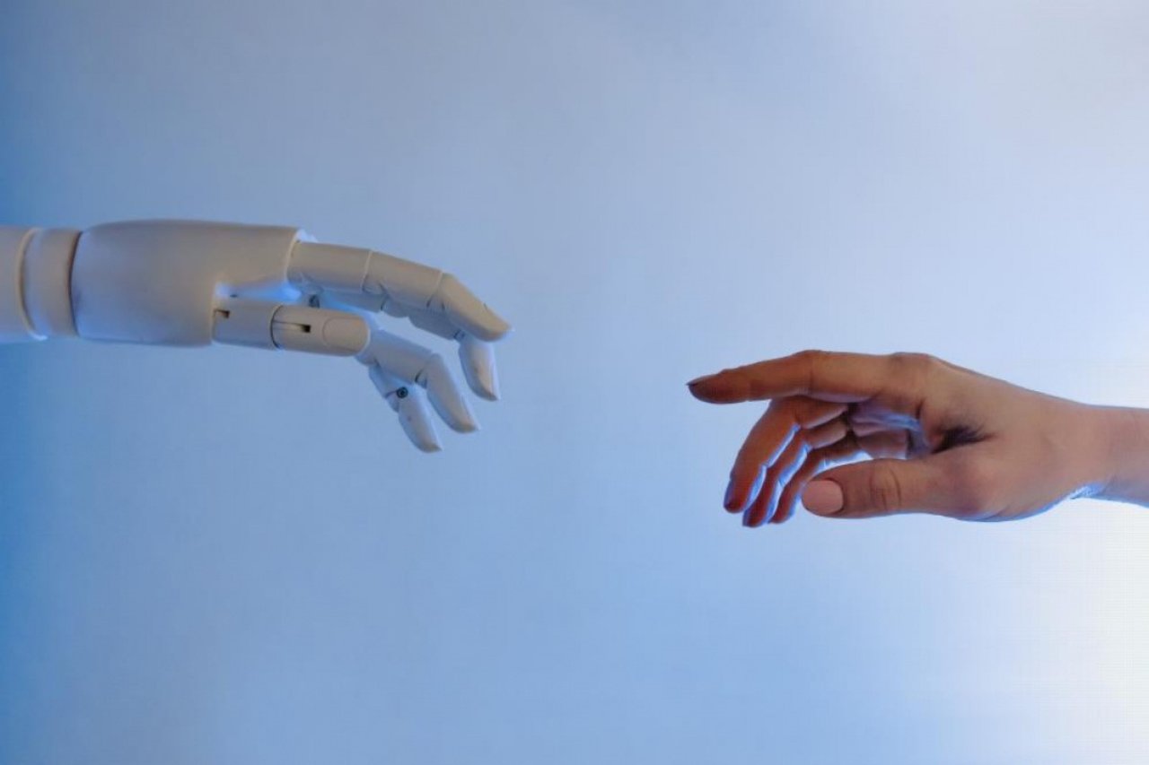 Robot eli ile insan elinin birbirine yaklaştığı yapay zekâ temalı görsel