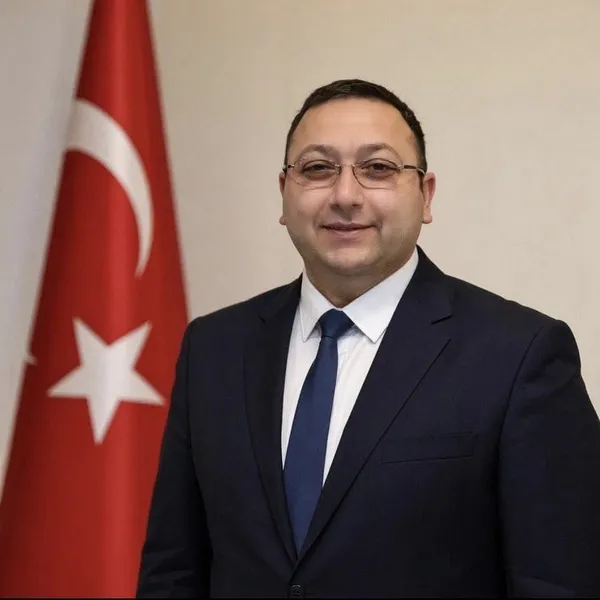Türk bayrağı önünde takım elbiseli bir yerel yönetici portresi.
