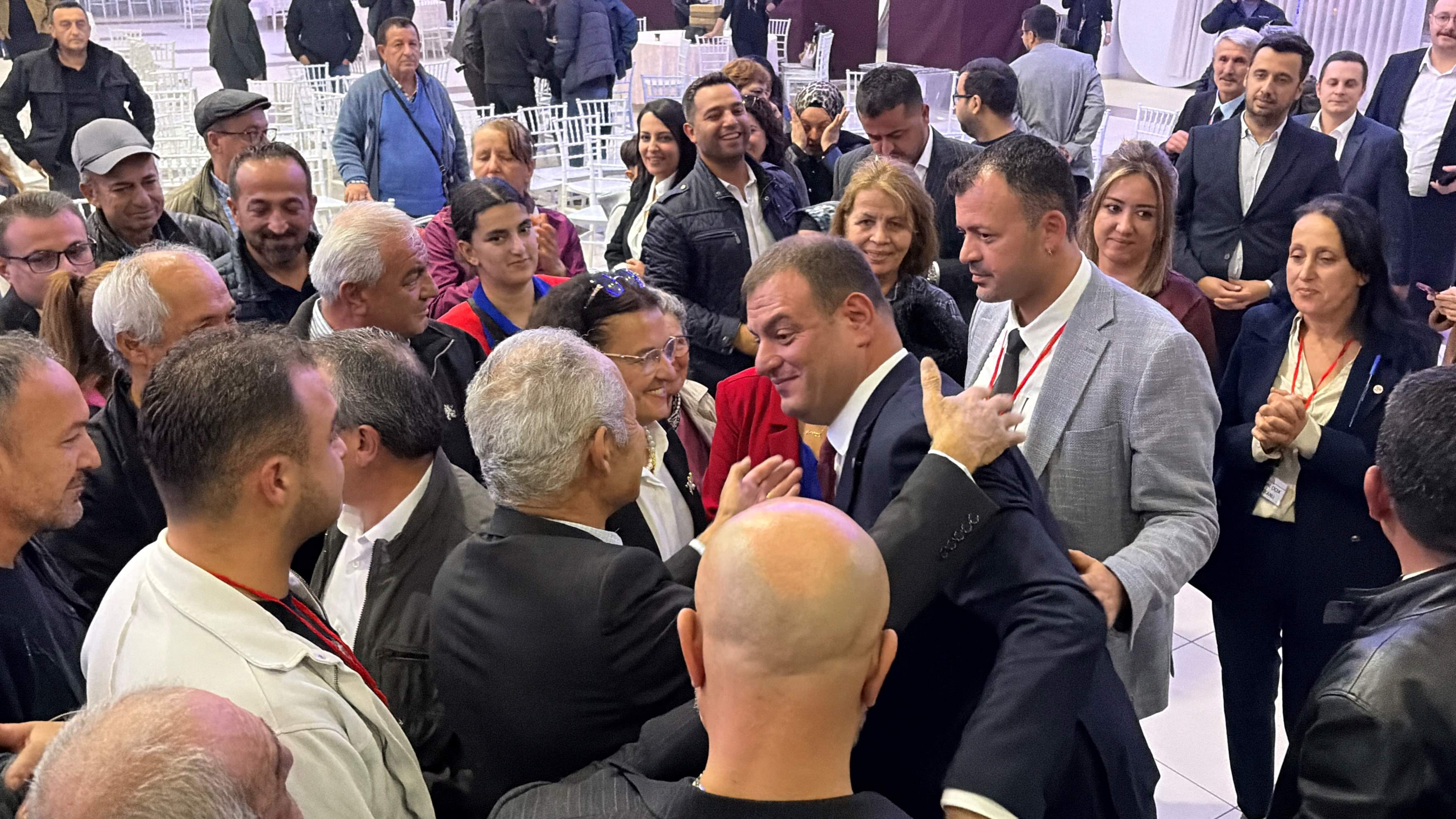 Toplantı salonunda birbirleriyle görüşen ve alkışlayan partililer.