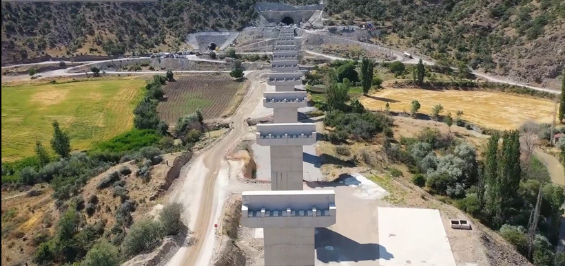 Bridge piers belonging to the high-speed train line under construction in a rural area and the construction road leading to the tunnel entrance.