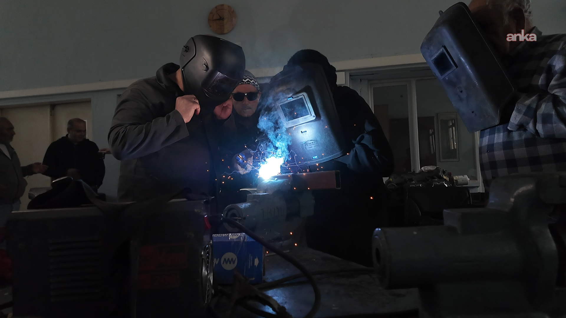 Kaynak maskesi takan kursiyerler atölyede metal parça üzerinde uygulama yapıyor.