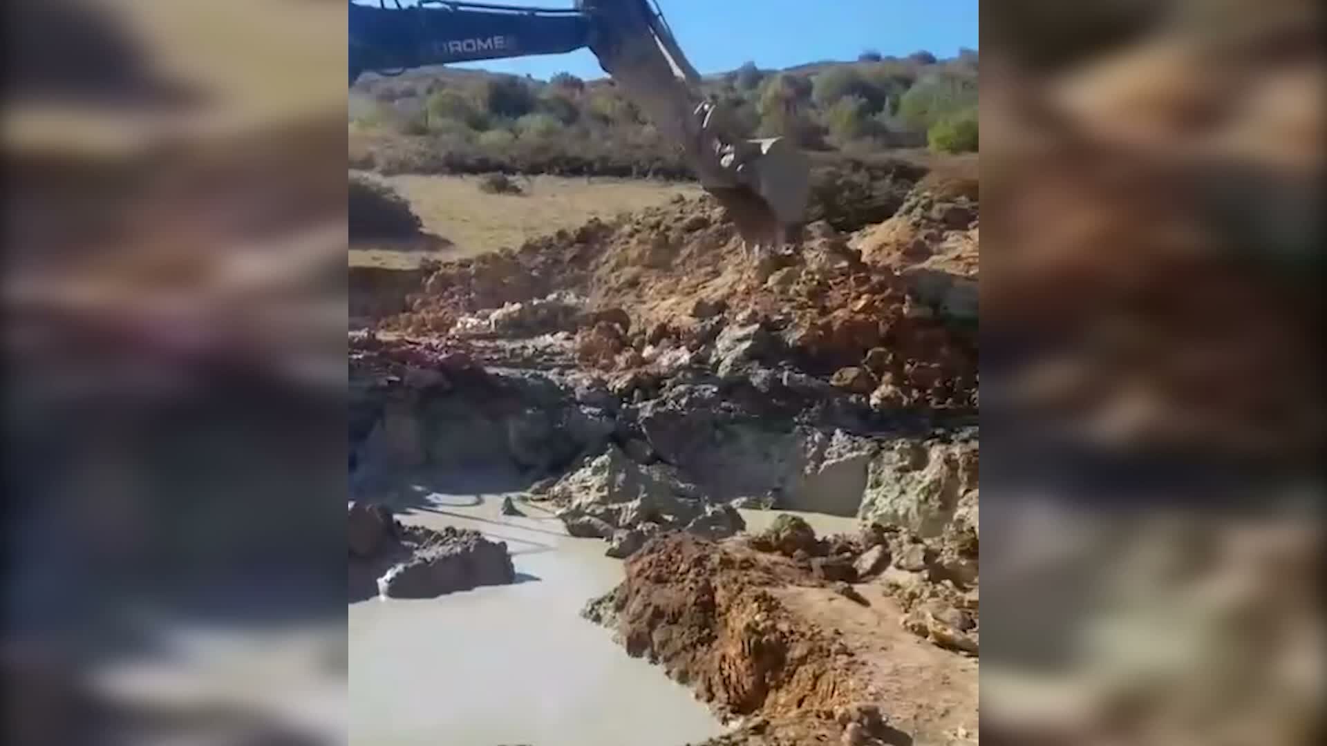 Dikey video karesinden alınmış, çamurlu kazı alanında çalışan ekskavatör.