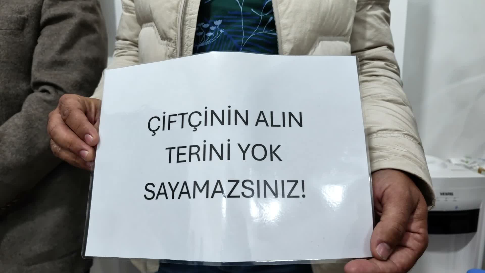 Bir kişinin elinde ‘Çiftçinin alın terini yok sayamazsınız’ yazılı dövizi tuttuğu yakın plan görüntü.