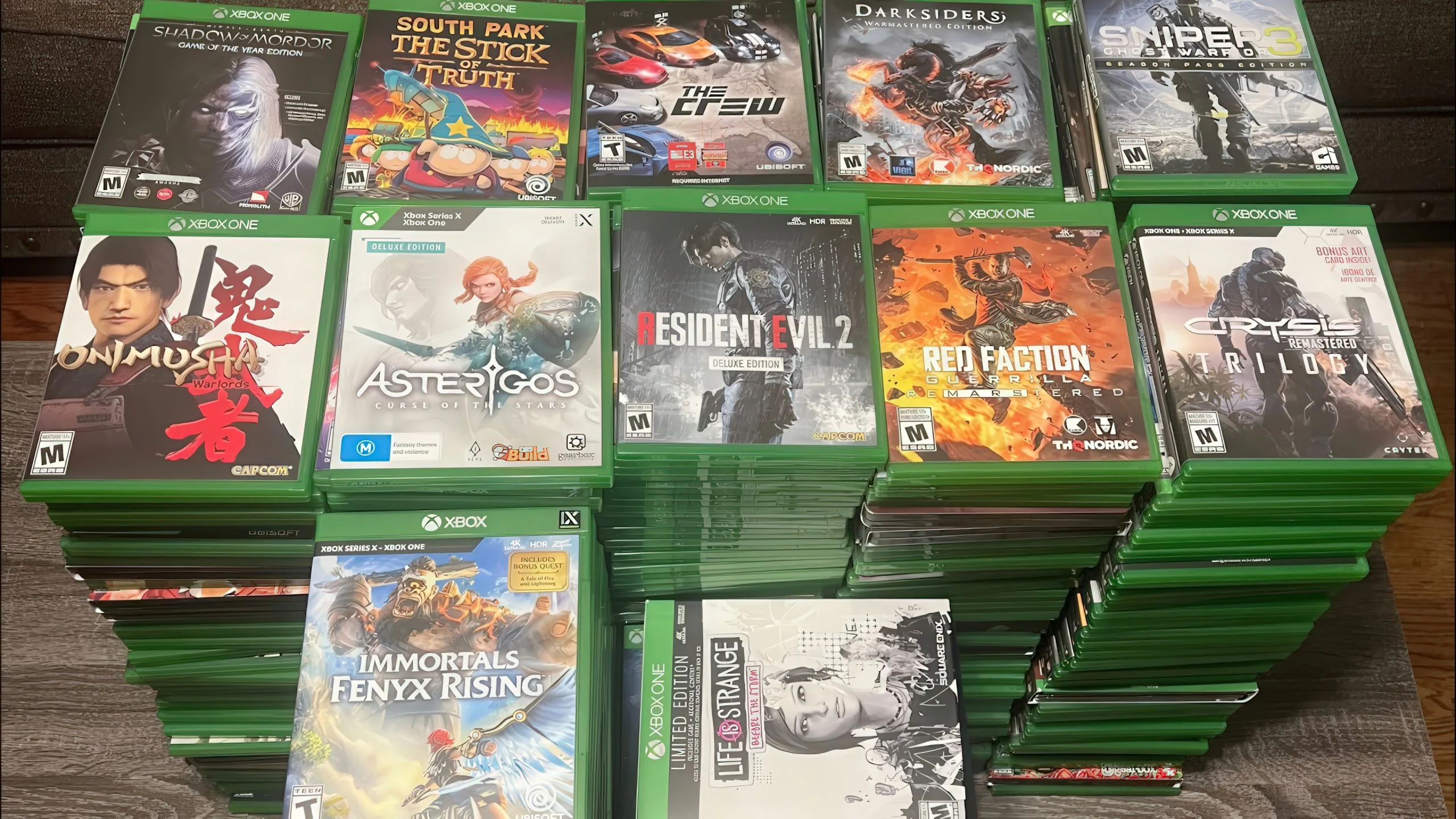 Many physical Xbox game cases lined up on a table.