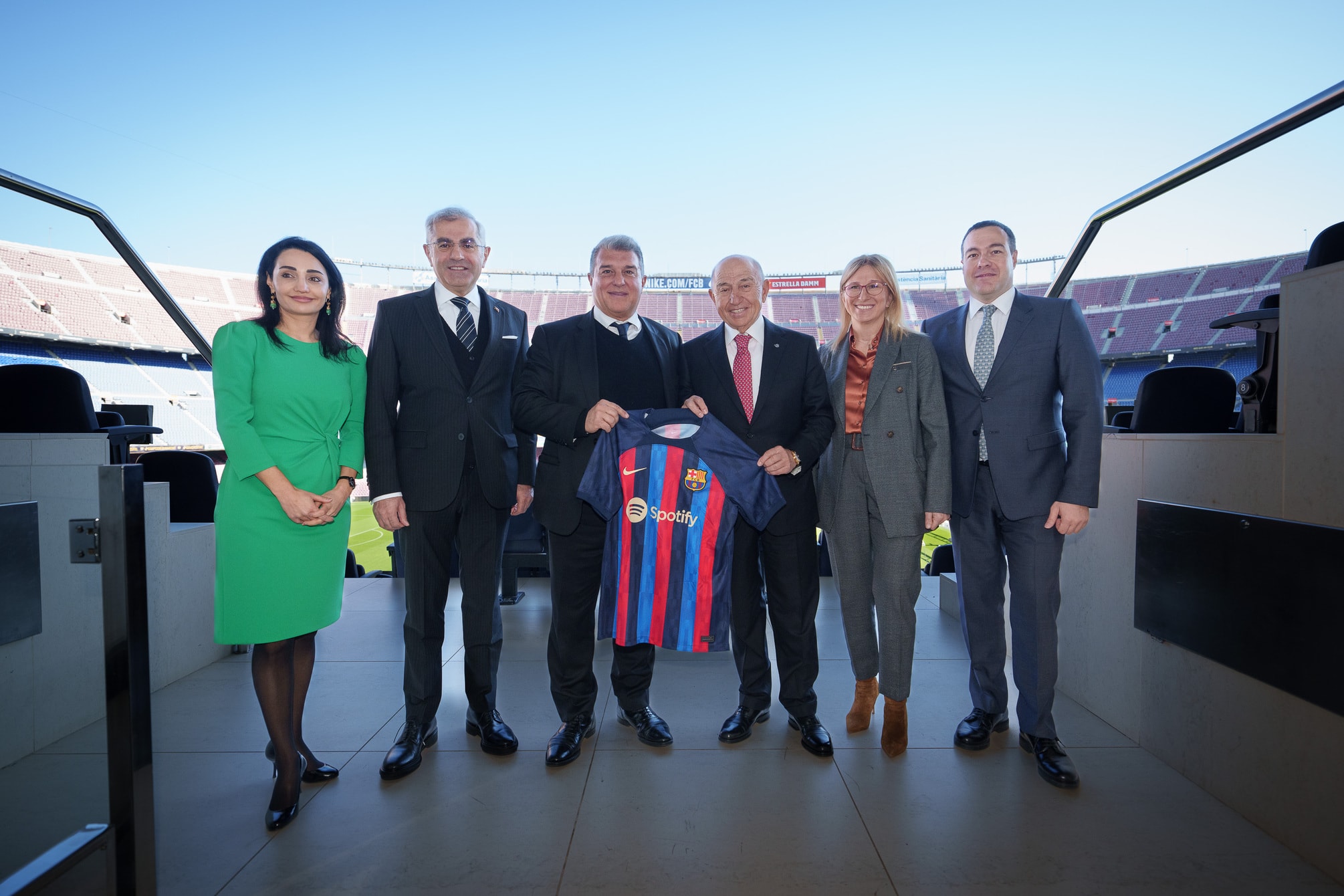Camp Nou tribünleri önünde Barcelona formasıyla poz veren kulüp ve şirket temsilcileri.