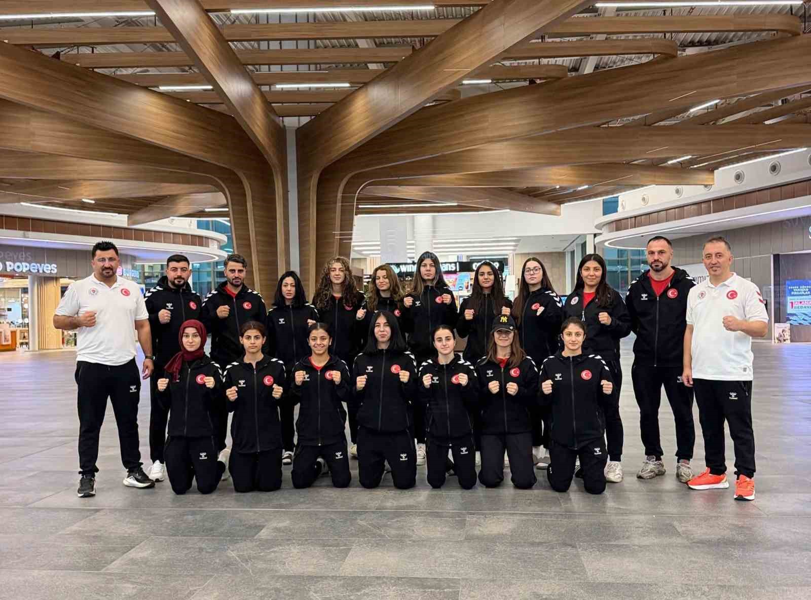 Milli boksörler ve antrenörlerden oluşan grup, spor kıyafetleriyle toplu fotoğraf için poz veriyor.